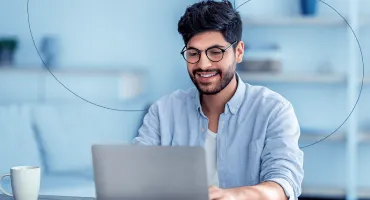 Homem sorrindo enquanto tecla no laptop