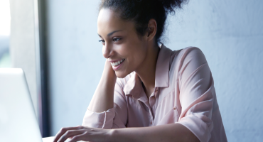 Mulher sorrindo enquanto tecla no laptop